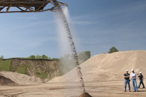 A misting ring encloses the material stream in a curtain of atomized mist